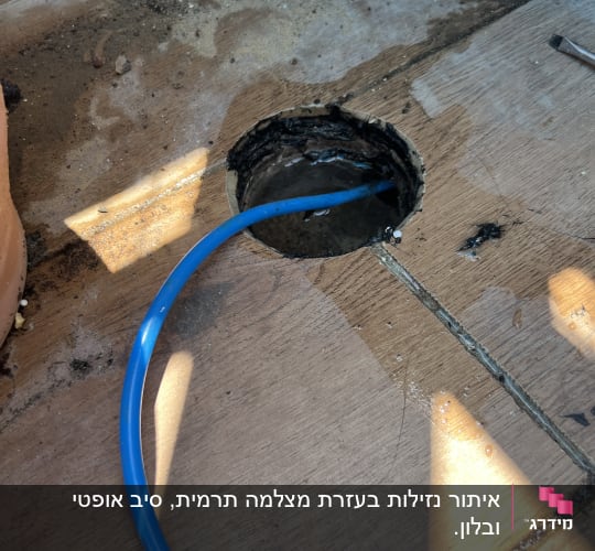 צינור כחול עובר דרך חור ברצפה ליד ניקוז